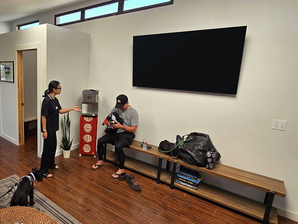 Members chatting by the bench and water cooler under the lounge TV