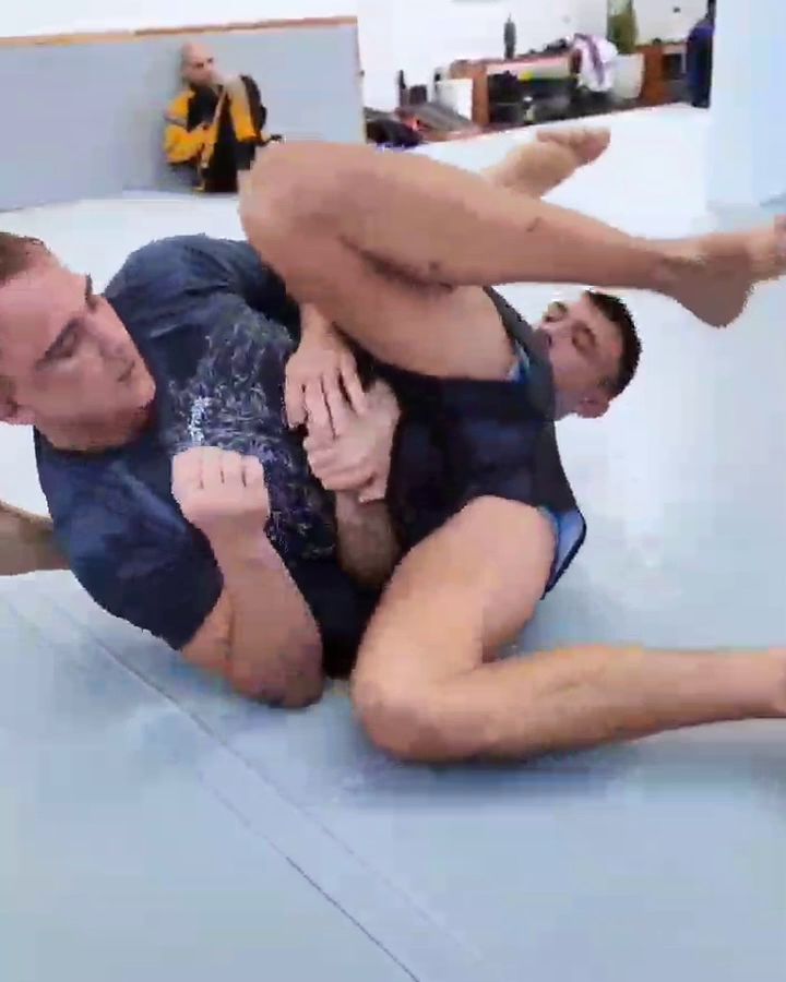 Open mat: pairs rolling under the round timer on the wall TV