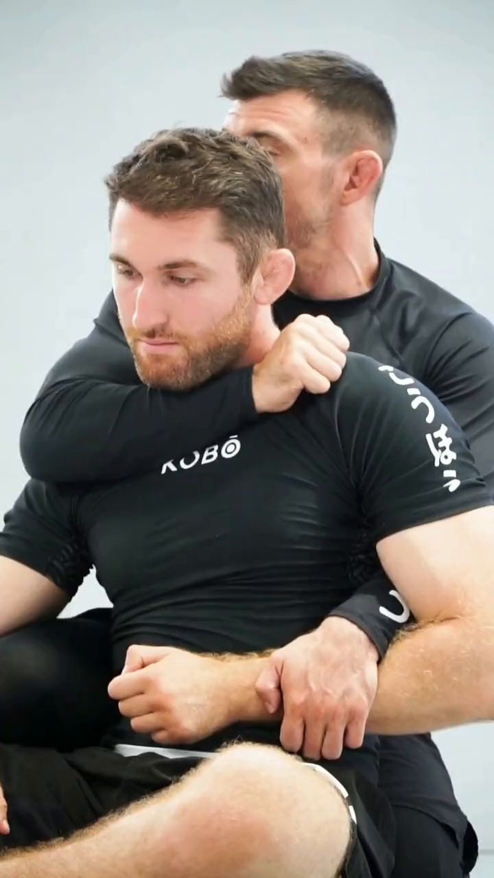 Two KŌBŌ grapplers drilling a seatbelt grip from the back